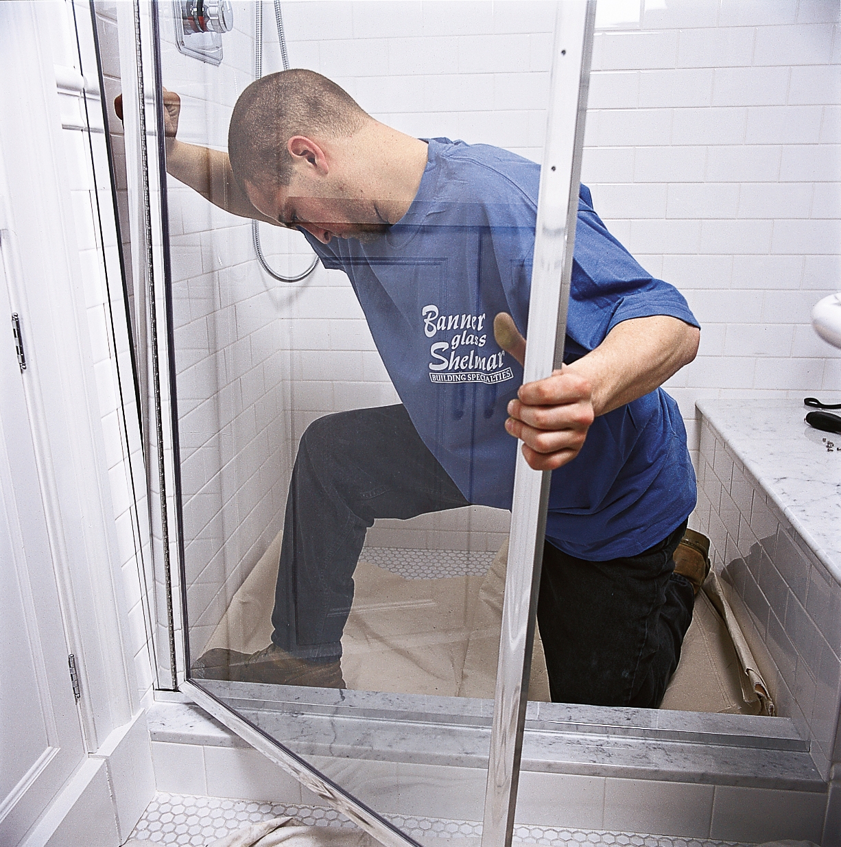 Мастер демонтирует стеклянную дверь в ванной комнате